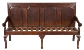 An 18th Century oak settle:, the rectangular back with quadruple fielded panels,