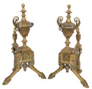 A pair of andirons in the Regency style: with fluted writhen neo-classical urns on a musical trophy