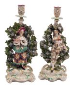 A pair of Derby bocage candlestick figures of the Italian Farmer and Wife: wearing colourful