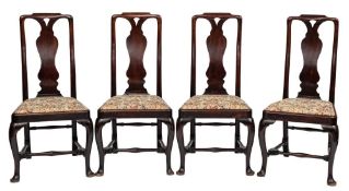 A set of four George II mahogany dining chairs: the curved backs with shaped toprails and pierced