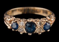 A sapphire and diamond seven-stone ring: between scroll shoulders, the shank stamped '500',