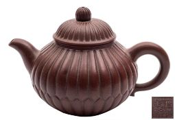 A Chinese Yixing teapot and cover: of ovoid form moulded as a chrysanthemum flower with bud finial,