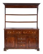 An 18th Century oak dresser:, the shelved superstructure with a moulded cornice,