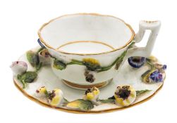 A Rockingham porcelain miniature cup and saucer: applied with leafy floral sprays, puce mark,