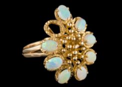A 14 carat gold opal dress ring: set with oval cabcohon opals surrounding a beaded centre,