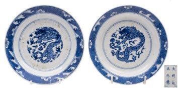 A pair of Chinese blue and white 'dragon' saucer dishes: each painted with a scaly dragon persuing