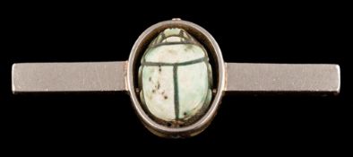 A scarab brooch: the faience scarab in an oval setting, on a bar brooch, 5.2cm long.