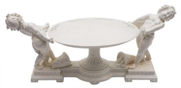 An English white porcelain centrepiece: in the form of a pierced oval tazza supported by two putti,