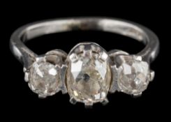 A graduated diamond three-stone ring: the central oval diamond between round old-cut diamonds,