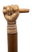 A 19th century marine ivory walking cane,: the pommel carved in the form of a fist holding a bar,