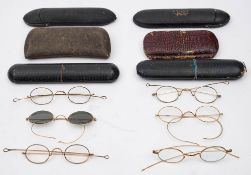Six pairs of gold plated spectacles in cases: including a pair with tinted lenses.