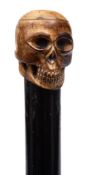 A 19th century marine ivory carved skull walking cane: mounted on an ebony shaft with marine ivory