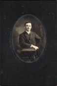 A black and white oval half-length studio portrait photograph of F E Davies: signed 'Frank' in blue