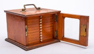A mid 20th century stained birch and pine table coin cabinet: having single glazed door enclosing