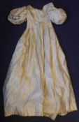 An early 19th century ivory silk dress: high waisted with panel front and puff short sleeves.