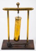 A trench art shell case dinner gong: the shell suspended between two brass column supports with