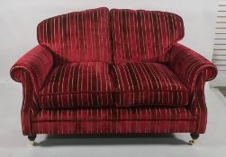 Pair of two-seater modern sofas in a burgundy ground striped upholstery, on turned supports to brass