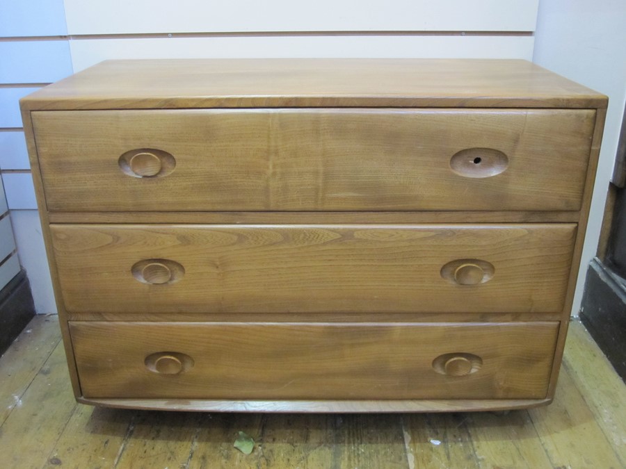 Ercol chest of three long drawers, on plinth base, with circular wooden handles (one missing),