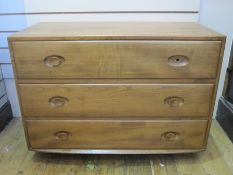 Ercol chest of three long drawers, on plinth base, with circular wooden handles (one missing),