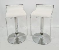 Pair of adjustable chrome stools on circular chrome bases, with chrome foot rests and white