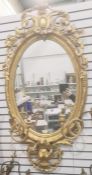 Decorative gilt girandole wall mirror of oval form with laurel leaf border, surmounted by floral