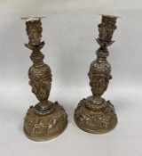 A pair of Indian/Burmese white coloured metal candlesticks, relief of warriors/hunters and