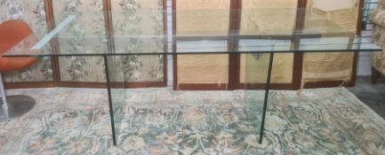 Plate glass and metal dining table, the two upright glass trestle legs united by a central metal