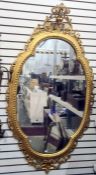 Decorative gilt wall mirror of shaped oval form, with a foliate scrolling outer border, 82cm wide