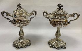 Pair of silver plated two handled lidded pedestal bowls, flower finials, scroll decorated, semi