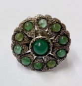 A silver coloured metal and emerald ring, possible Indian, circular/flower shaped with central