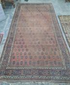 Eastern rug repeated hook medallion to a central red ground field, stepped border, 473 x 238cm