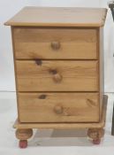 Modern pine bedside table fitted with three short drawers, on bun feet and plastic castors, 44cm