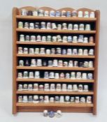Collection of thimbles on a wooden hanging display shelf including examples by Spode, Wyeside,