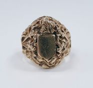 9ct gold gentleman's signet ring, the central blank shield surrounded by elaborate decoration of