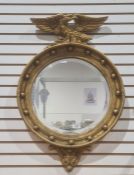 20th century circular mirror in gilt-effect frame surmounted by eagle, 68cm x 45.5cm