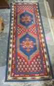 Modern Eastern-style runner with two central medallions on a red ground, stepped border, 210cm x