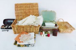 Wicker picnic basket filled with assorted linens and textiles, table ware, another basket, a