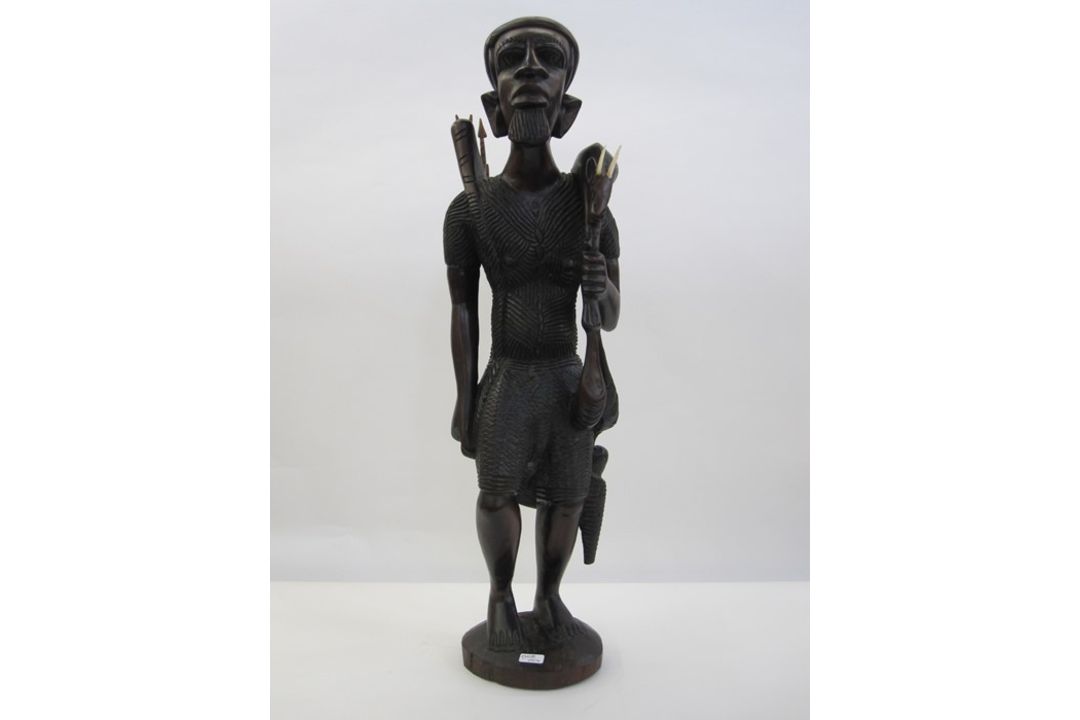 Large African carving of man with spear, wearing hat and carrying kill, 70cm high approx.