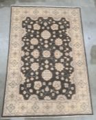 Modern Eastern-style black ground rug, the central field with foliate decoration, on a cream