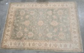 Modern pale green ground Eastern-style rug with foliate decoration to the central field, cream