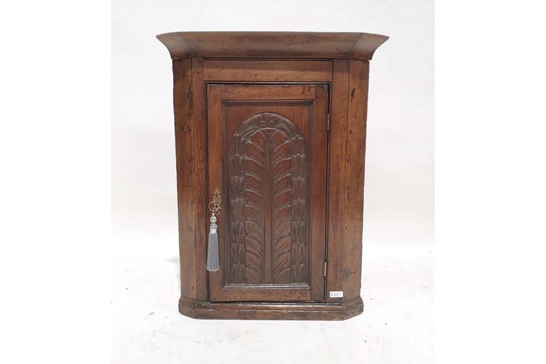 19th century oak wall-hanging corner cupboard, the single door with carved decoration enclosing