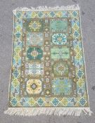 Modern green ground rug, the central field with ten panels in blues, greens and yellows, 120cm x