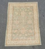 Pale green ground modern Eastern-style rug with foliate decoration to the central field, cream