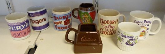 Two boxes of assorted mugs advertising Cadbury's chocolate to include Dairy Milk, Chocolate Buttons,