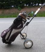 Golf clubs within a golf caddy on wheels and the golf clubs seem to be mainly by Tanaka