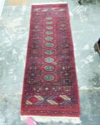 Eastern style red ground rug with ten elephant foot gul pattern in centre, with geometric border and