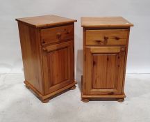 Pair of 20th century pine bedside tables with single drawers above cupboard doors, on squat bun