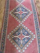 A Persian wool runner in red, blue and white with lozenge design, 370cm x 88cm