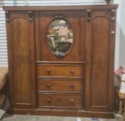 19th century wardrobe, oval mirrored central door over three drawers flanked by wardrobe doors on