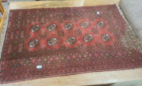 Red ground Eastern-style rug, the central field with ten elephant foot guls, stepped border, 117cm x